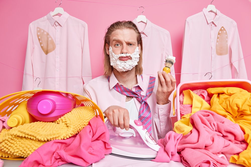 man-holds-iron-shaving-brush-busy-ironing-laundry-clothes-works-hard-weekends-poses-clotheslines-pink.jpg